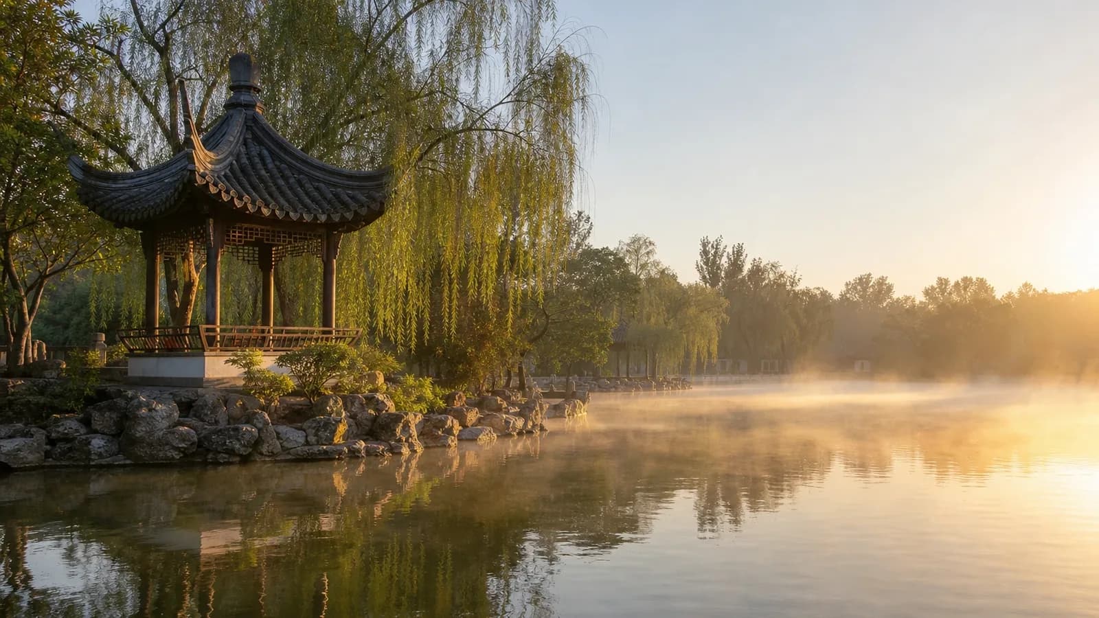 A traditional Chinese pavilion beside a misty lake at sunrise